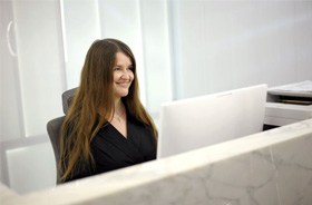 Smiling woman behind dental office front desk