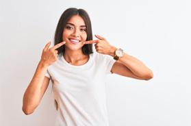Woman in white t-shirt pointing at her teeth