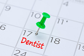 Dentist appointment marked on calendar with green thumbtack