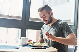 Man in gray shirt sitting at table, enjoying healthy meal