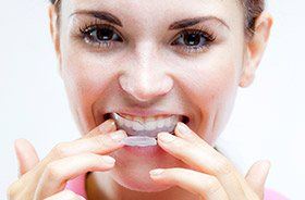 Woman using at-home teeth whitening kit