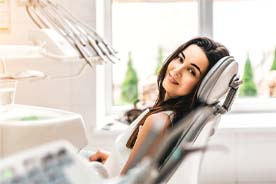 Woman reclining in dentist’s chair, ready for emergency treatment