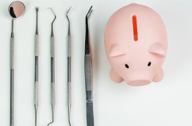 Piggy bank next to variety of dental instruments