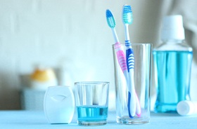Floss, mouthwash, and toothbrushes lined up on countertop