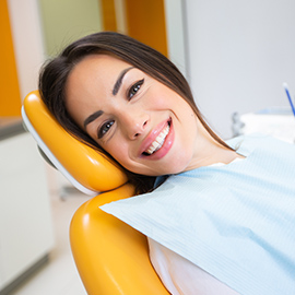 Man in dental chair looking at her smile in the mirror