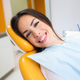 Young woman laying in dental chair and grinning