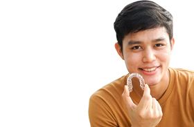 young man holding up aligner for Invisalign® in Torrington