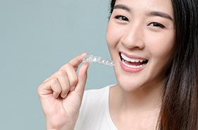 Happy woman holding aligner for Invisalign in Torrington