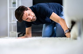 Man looking under furniture for lost Invisalign aligner