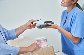 Male patient paying for care at dental office front desk