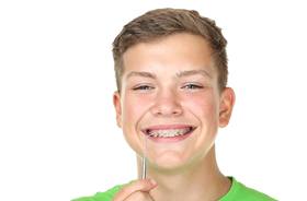 Teen boy using specialized tool to care for his braces