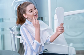 Dental patient using mirror to admire her new veneers