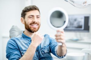 Man using mirror to examine his temporary veneers in Torrington