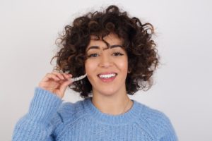 Woman holding aligner during Invisalign treatment in Torrington