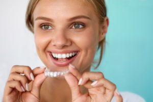 Woman holding Invisalign aligner close to her mouth