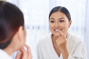 Woman leaning toward mirror, looking at her teeth