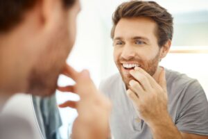 Young man in front of mirror, looking closely at his teeth