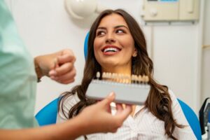 Patient smiling while dental team member holds shade guide